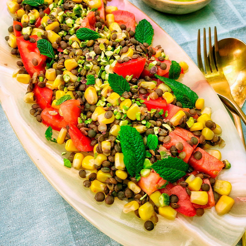 Ensalada de tomate, lentejas, maíz con aceite de menta y pistachos